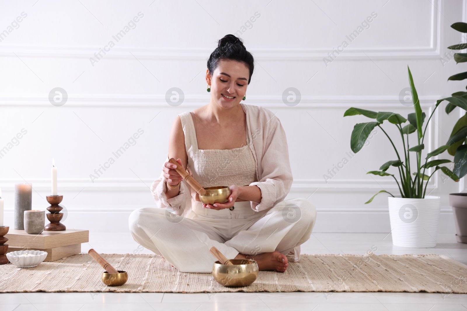 Photo of Woman with singing bowls on floor indoors