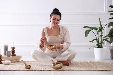 Photo of Woman with singing bowls on floor indoors