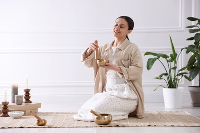 Woman with singing bowls on floor indoors. Space for text