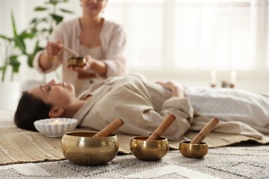 Photo of Woman undergoing singing bowl therapy indoors, selective focus. Space for text