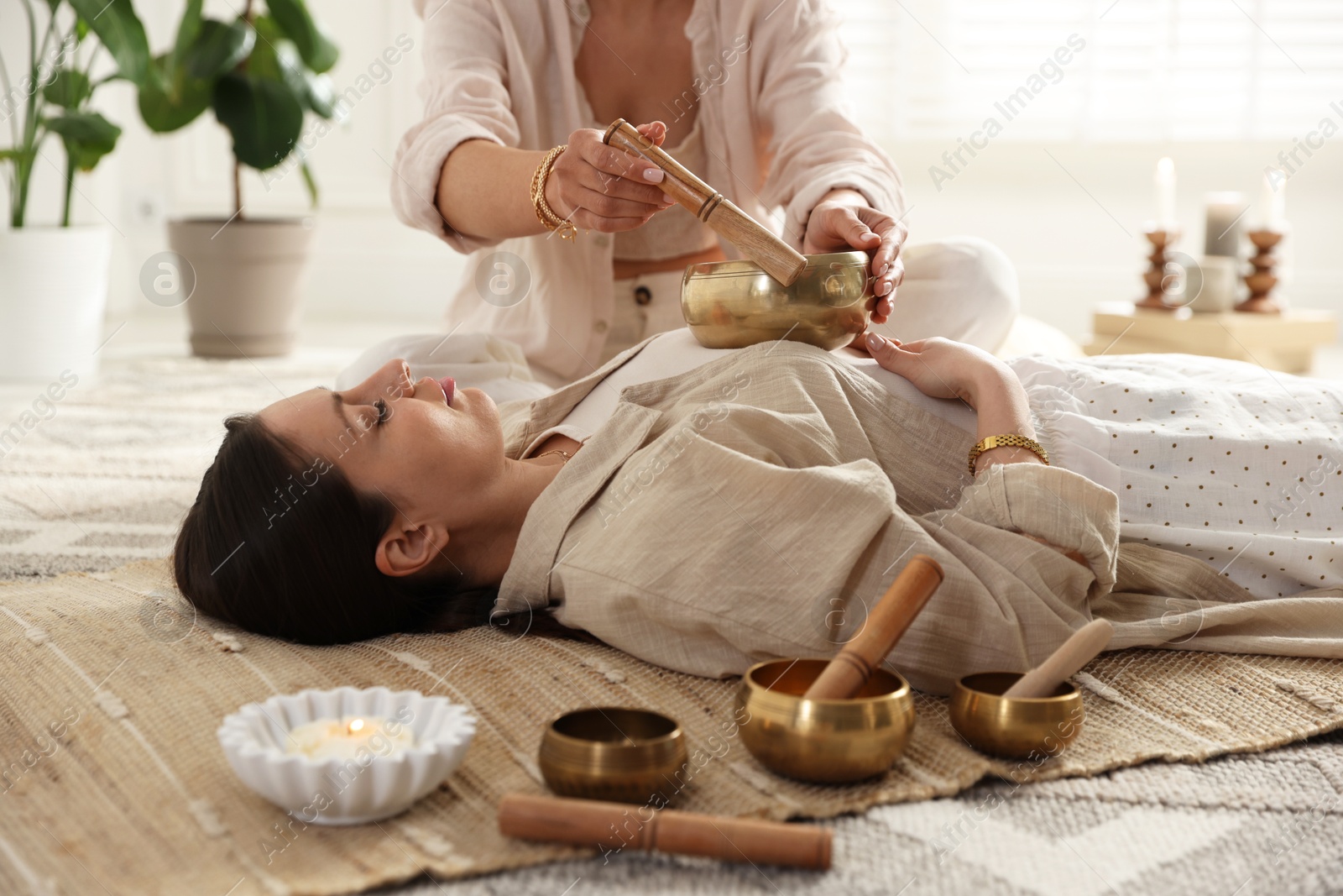 Photo of Woman undergoing singing bowl therapy lying on floor indoors