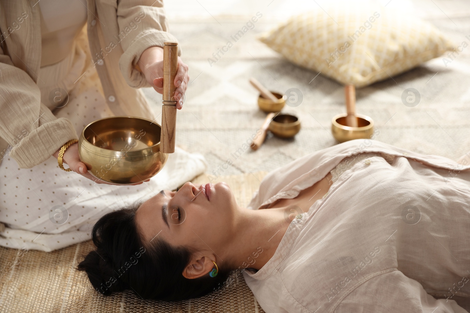 Photo of Woman undergoing singing bowl therapy lying on floor indoors