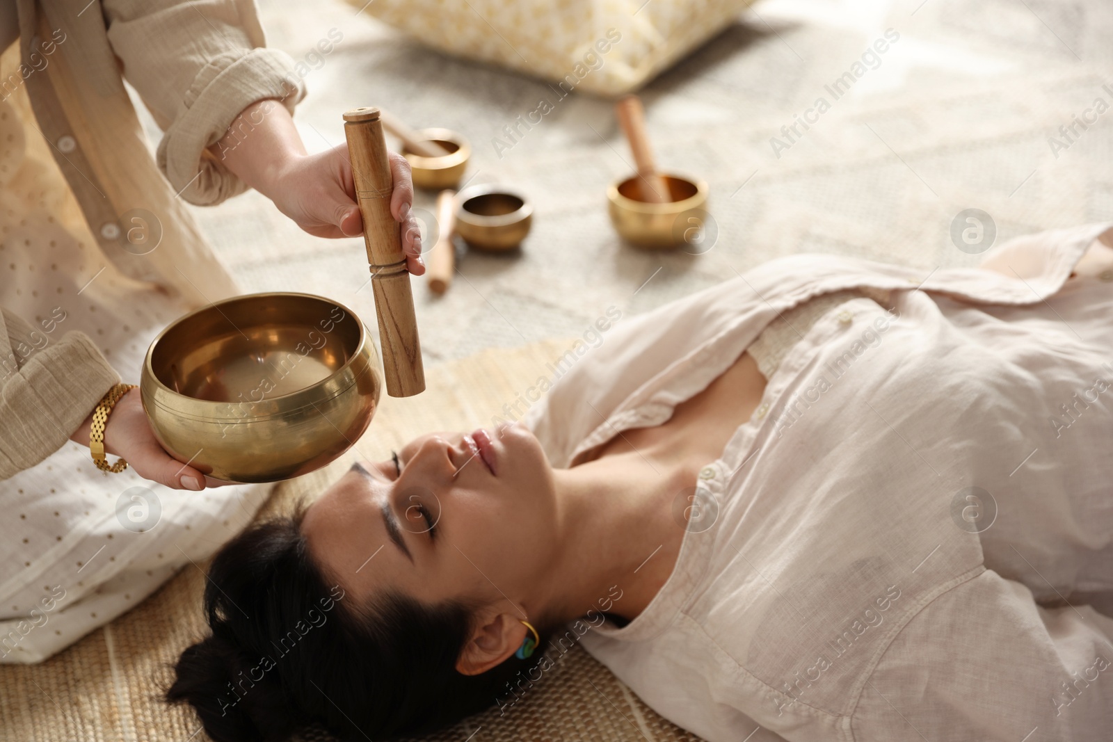 Photo of Woman undergoing singing bowl therapy lying on floor indoors