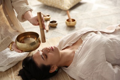 Photo of Woman undergoing singing bowl therapy lying on floor indoors