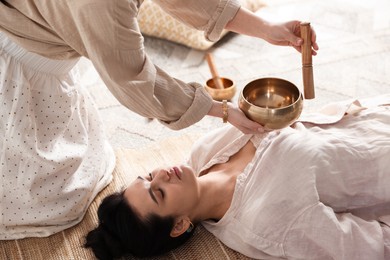 Photo of Woman undergoing singing bowl therapy lying on floor indoors