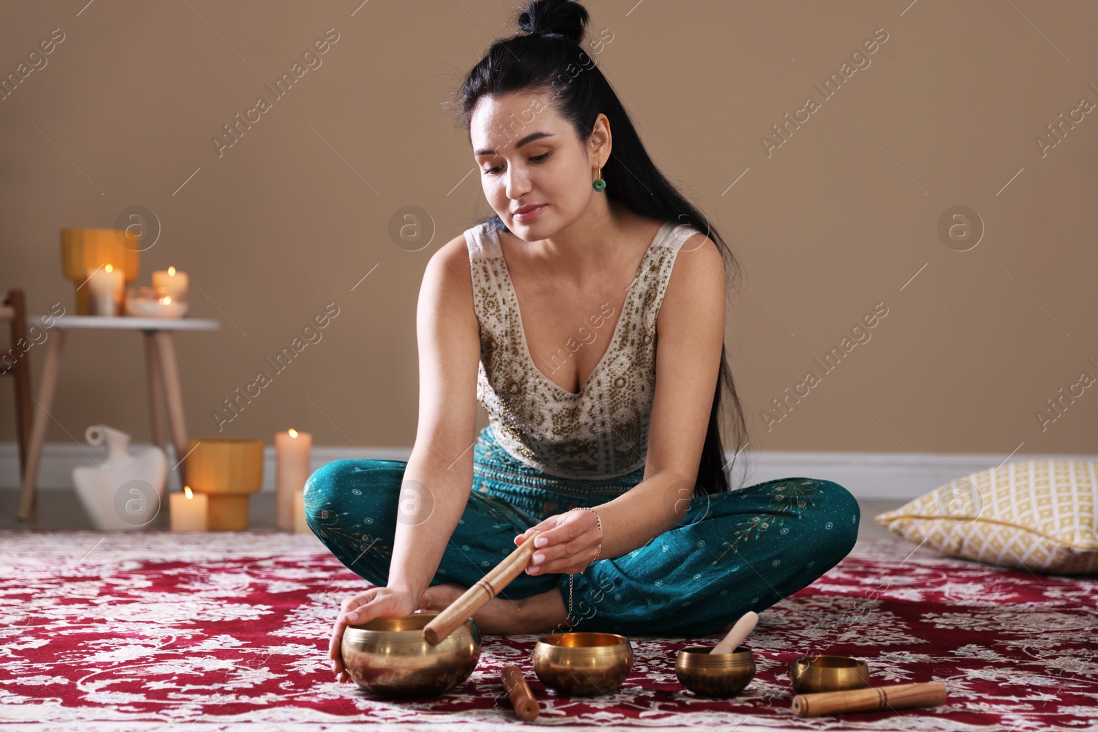 Photo of Woman with singing bowls and burning candles indoors