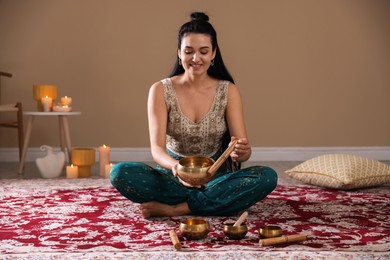 Photo of Woman with singing bowls and burning candles indoors