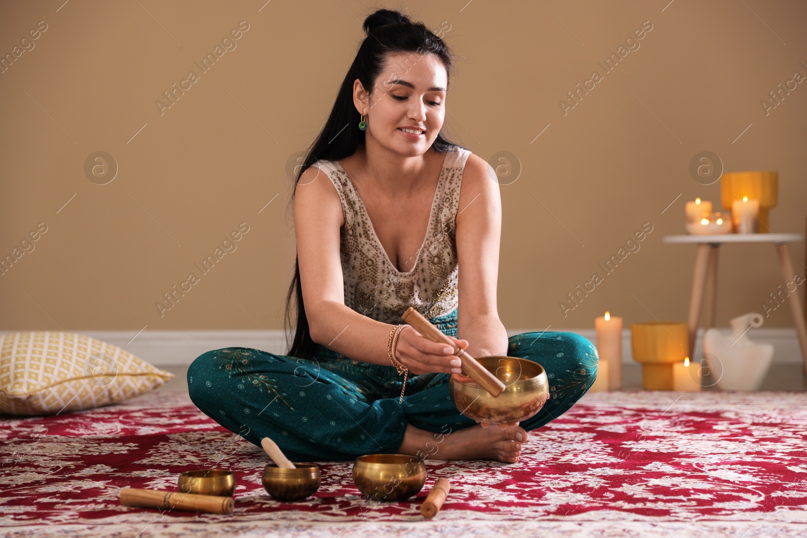 Photo of Woman with singing bowls and burning candles indoors