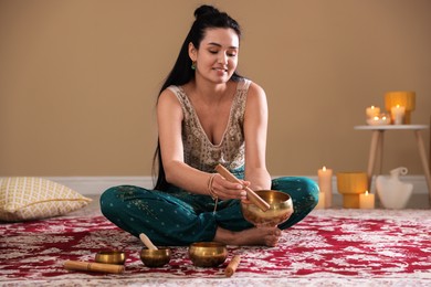 Photo of Woman with singing bowls and burning candles indoors