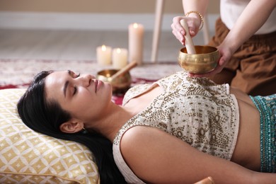 Photo of Woman undergoing singing bowl therapy lying on floor indoors