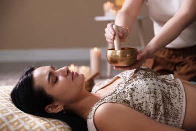 Photo of Woman undergoing singing bowl therapy lying on floor indoors