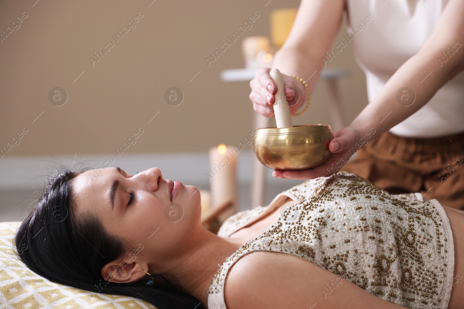 Photo of Woman undergoing singing bowl therapy lying on floor indoors