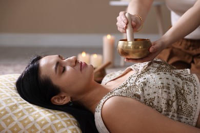 Woman undergoing singing bowl therapy lying on floor indoors