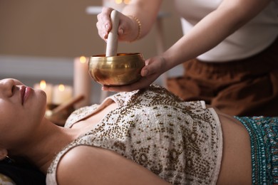 Woman undergoing singing bowl therapy indoors, closeup