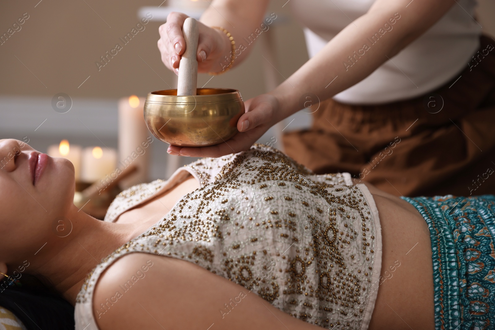 Photo of Woman undergoing singing bowl therapy indoors, closeup