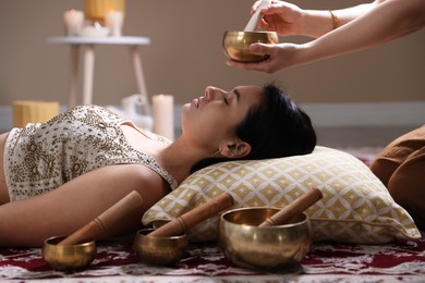 Woman undergoing singing bowl therapy lying on floor indoors