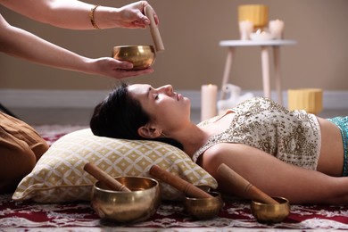 Photo of Woman undergoing singing bowl therapy lying on floor indoors