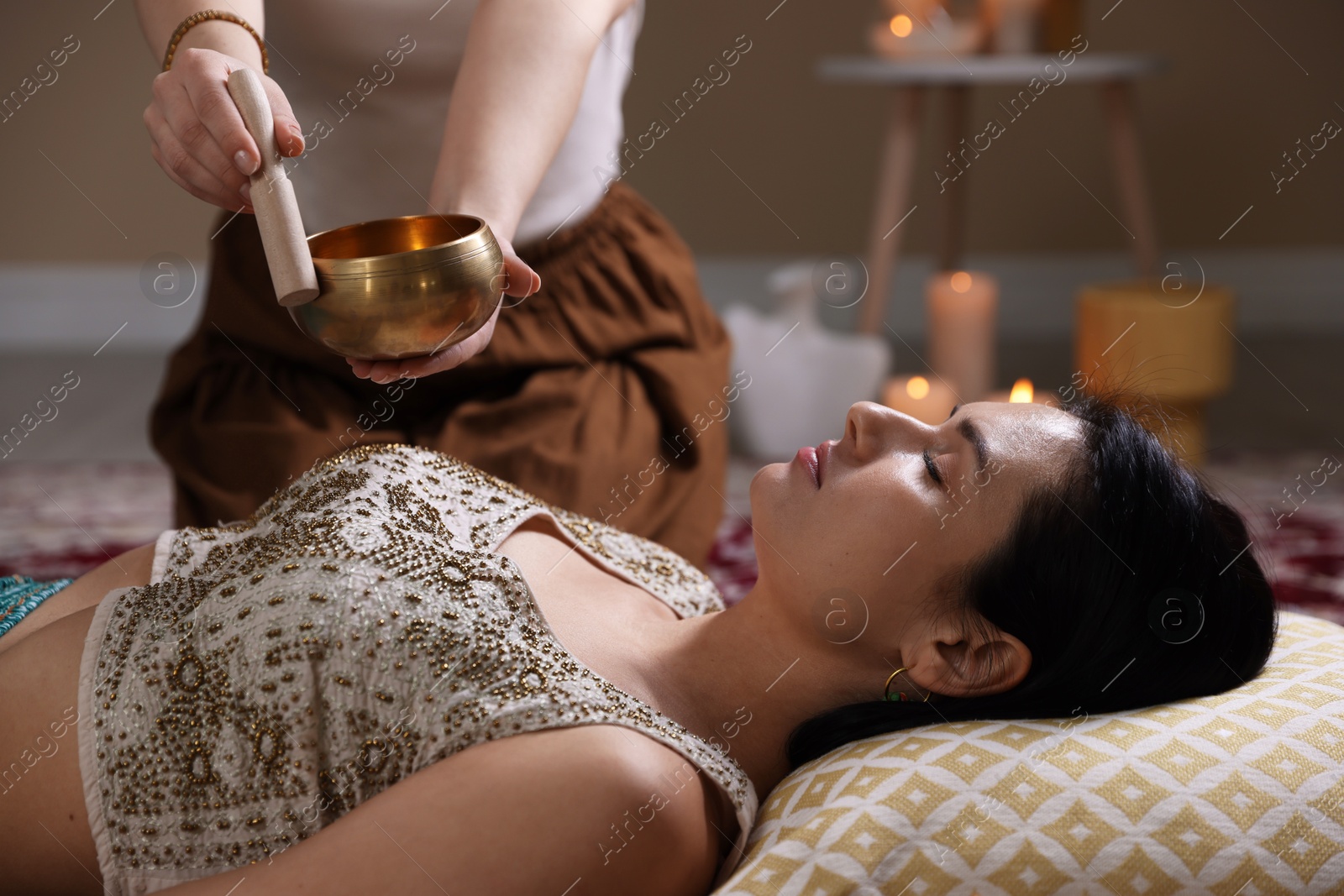 Photo of Woman undergoing singing bowl therapy lying on floor indoors