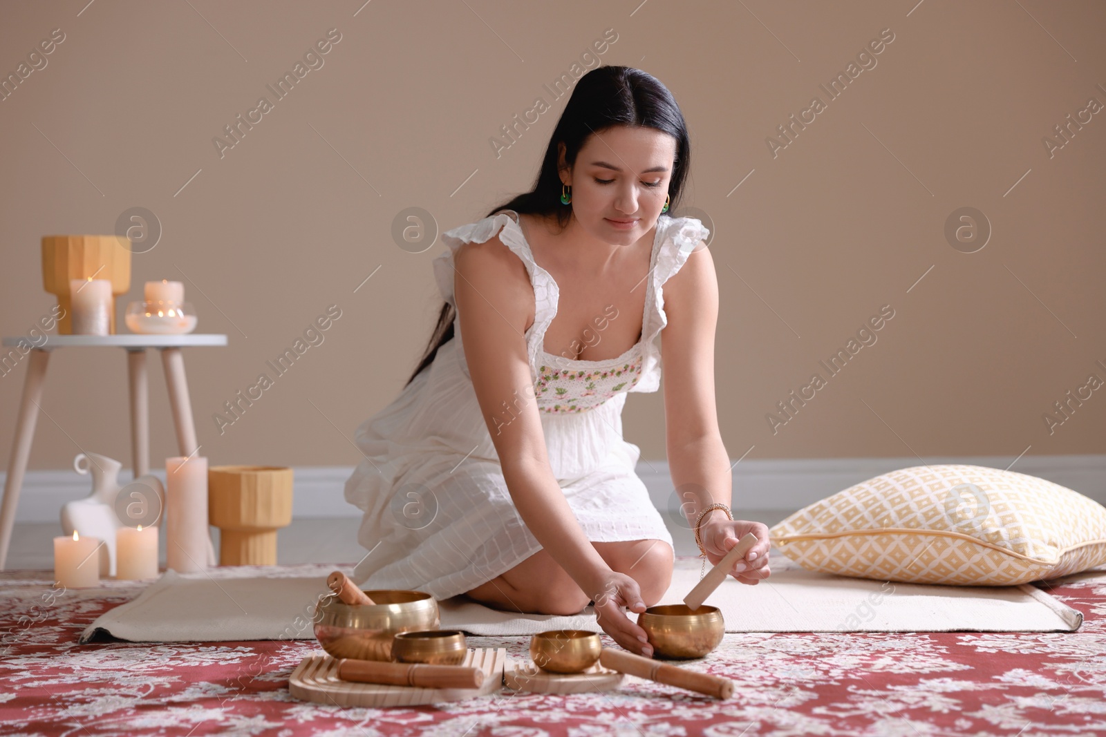 Photo of Woman with singing bowls and burning candles indoors