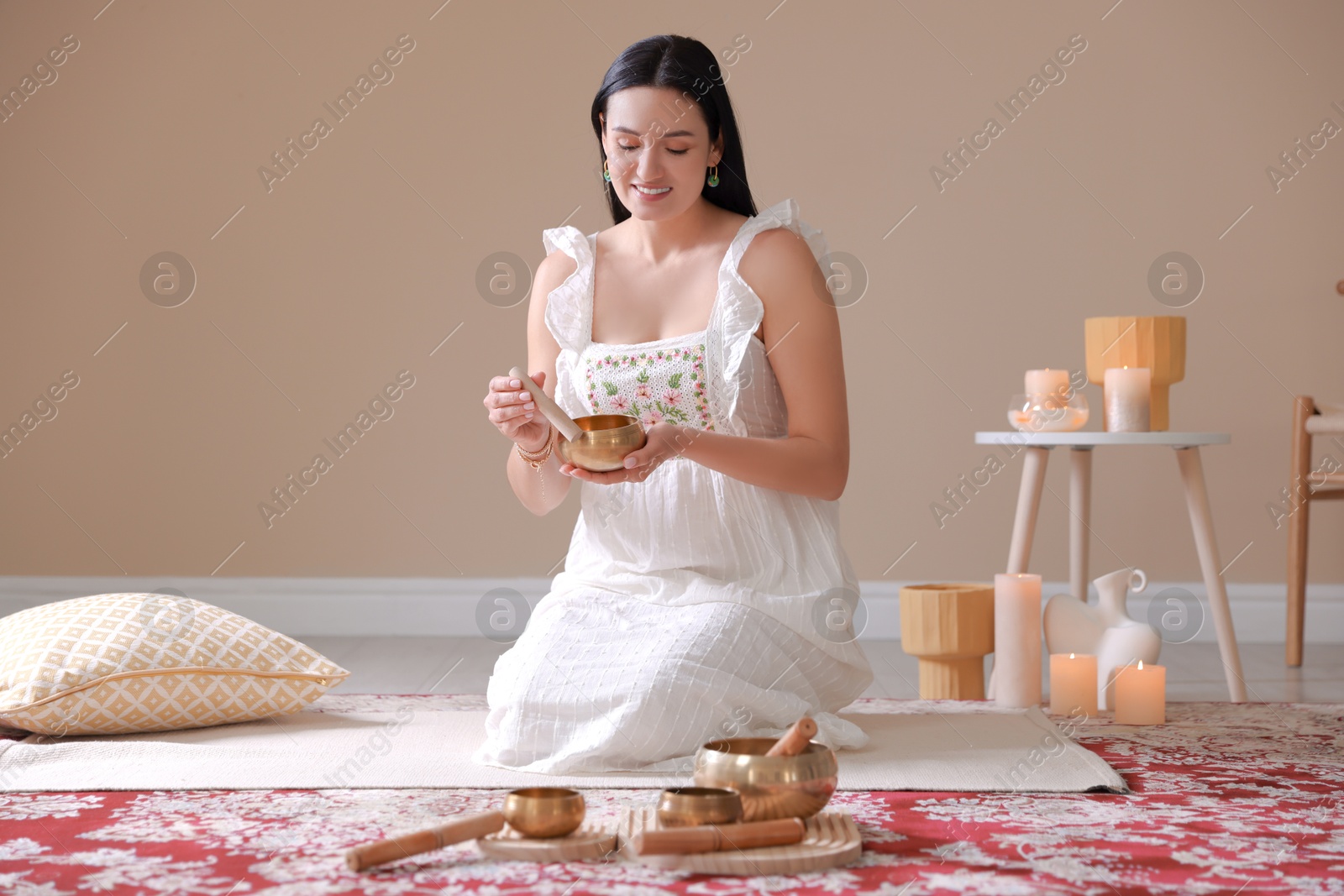 Photo of Woman with singing bowls and burning candles indoors