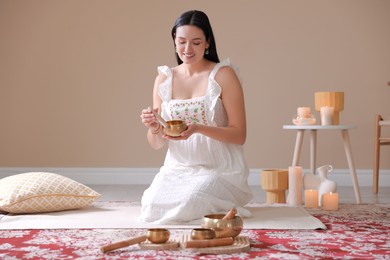 Photo of Woman with singing bowls and burning candles indoors