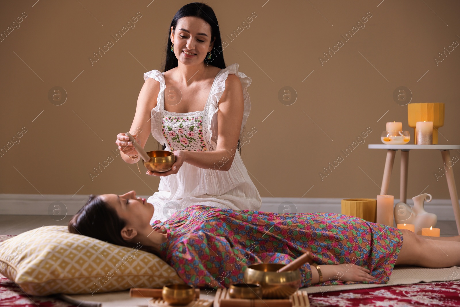 Photo of Woman undergoing singing bowl therapy lying on floor indoors