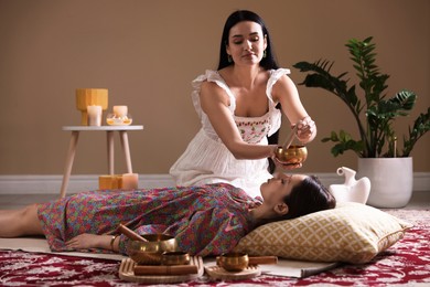 Woman undergoing singing bowl therapy lying on floor indoors