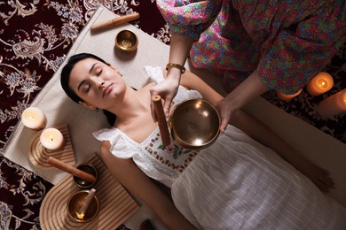 Photo of Woman undergoing singing bowl therapy indoors, top view