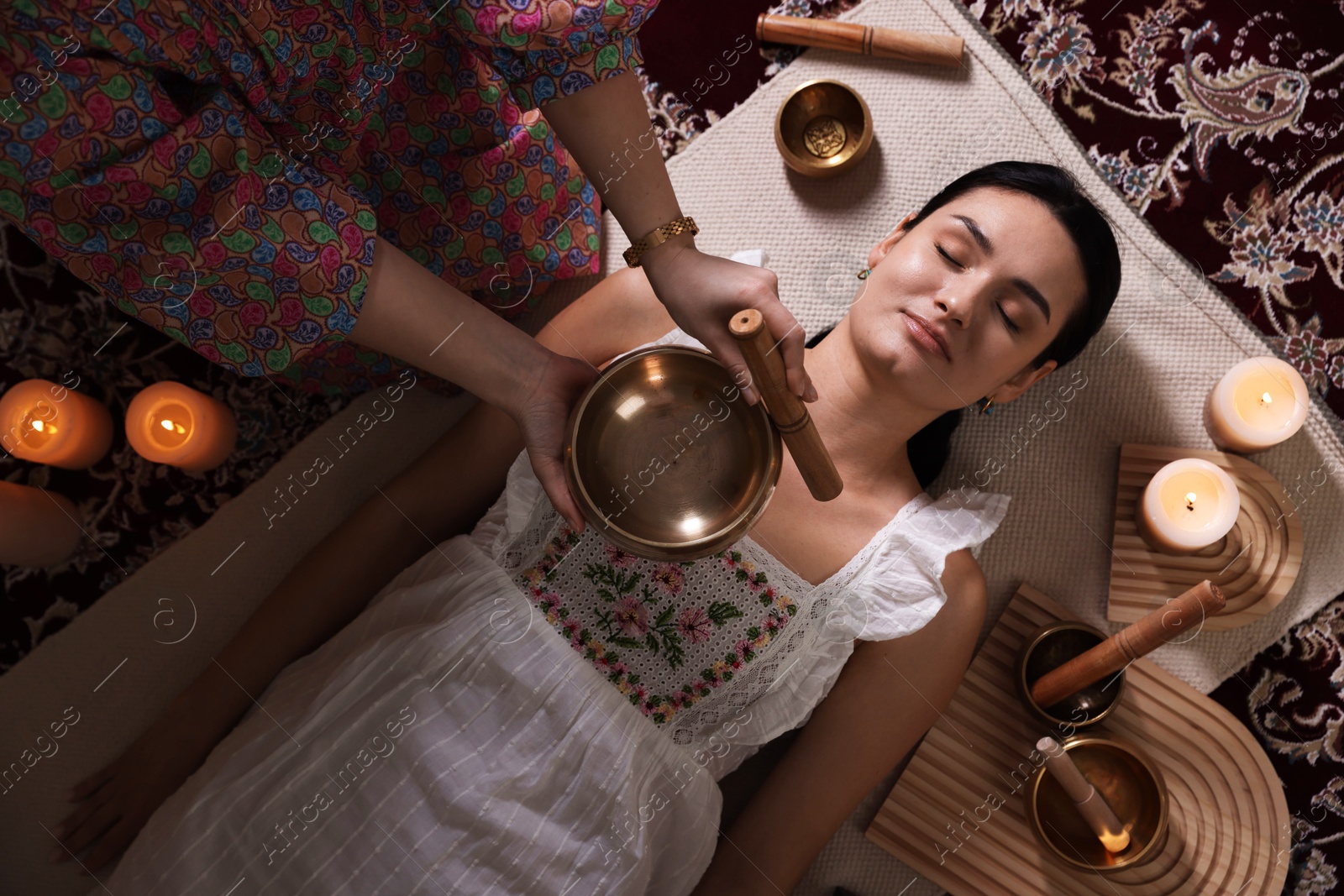 Photo of Woman undergoing singing bowl therapy indoors, top view