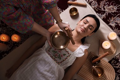 Woman undergoing singing bowl therapy indoors, top view