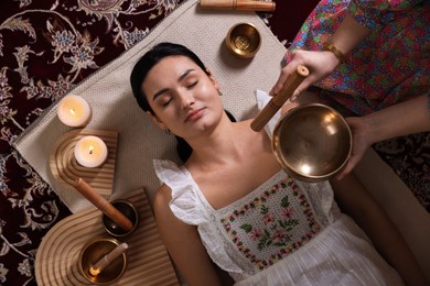 Photo of Woman undergoing singing bowl therapy indoors, top view