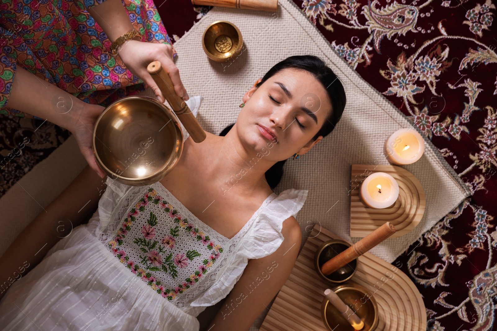 Photo of Woman undergoing singing bowl therapy indoors, top view