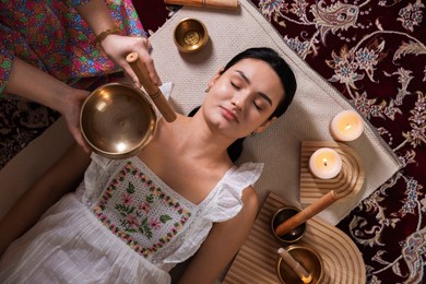 Photo of Woman undergoing singing bowl therapy indoors, top view