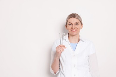 Photo of Professional dentist with tools on white background. Space for text