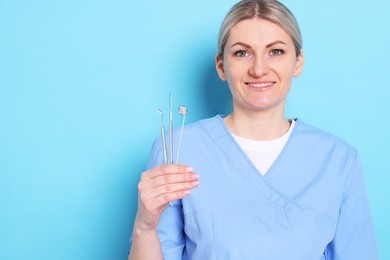 Photo of Professional dentist with tools on light blue background. Space for text