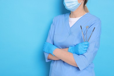 Photo of Professional dentist with tools on light blue background, closeup. Space for text