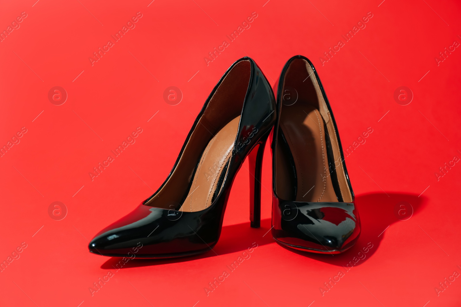 Photo of Black high heeled shoes on crimson background