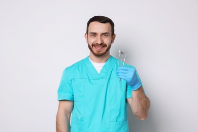 Professional dentist with tools on light background