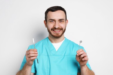 Photo of Professional dentist with tools on light background