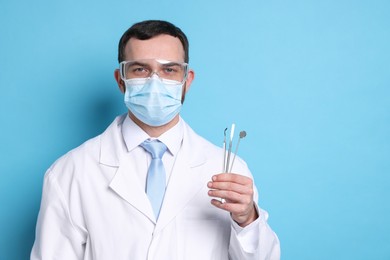 Photo of Professional dentist with tools on light blue background. Space for text