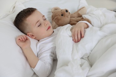 Photo of Bedtime. Cute boy sleeping with his teddy bear in bed