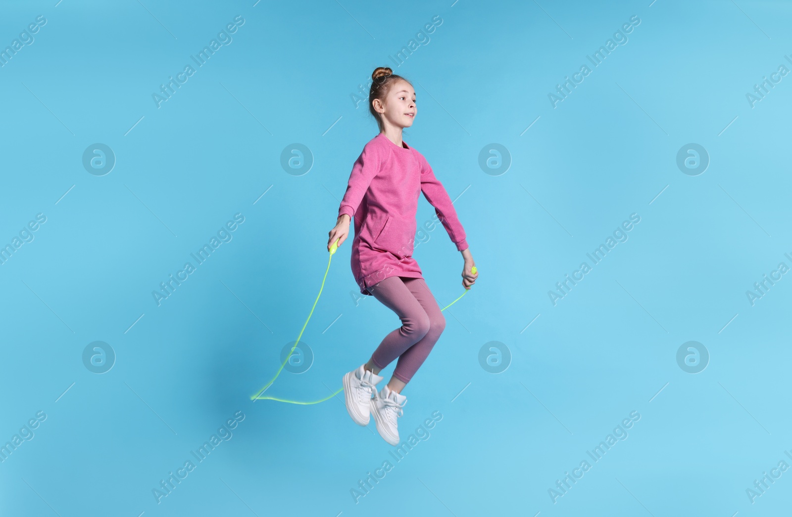 Photo of Cute little girl with jump rope on light blue background