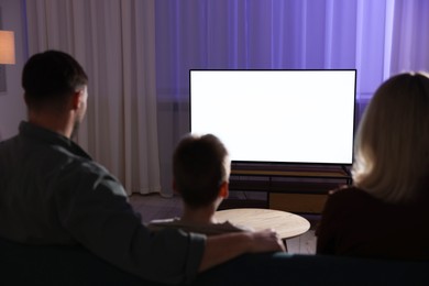 Photo of Happy family watching tv together at home in evening, back view