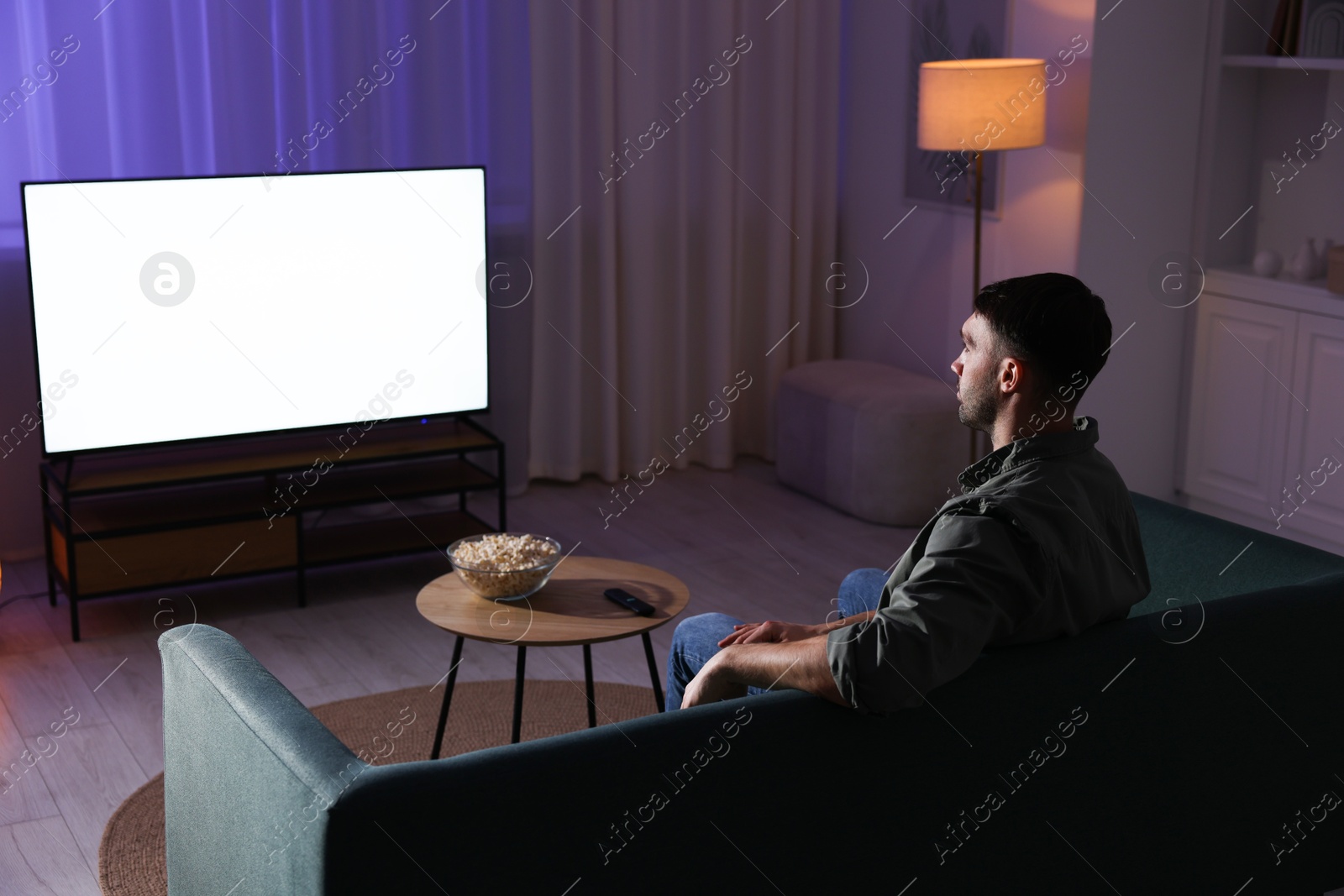 Photo of Man watching tv at home in evening