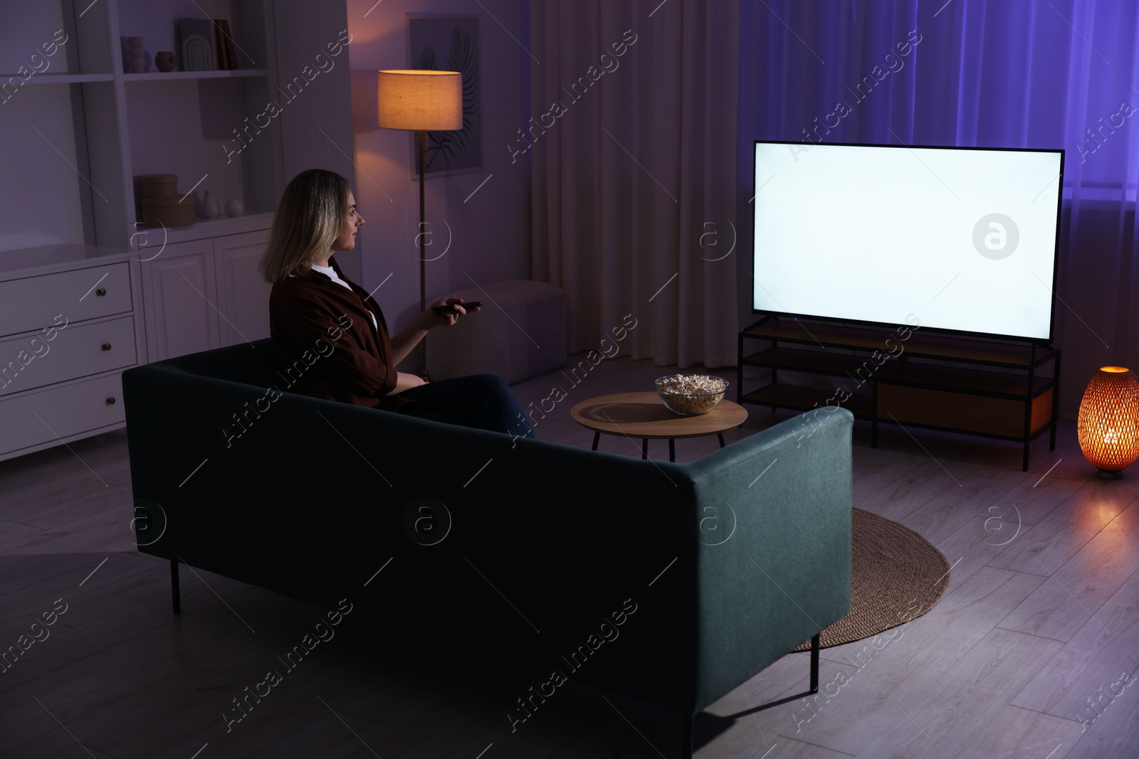 Photo of Woman watching tv at home in evening