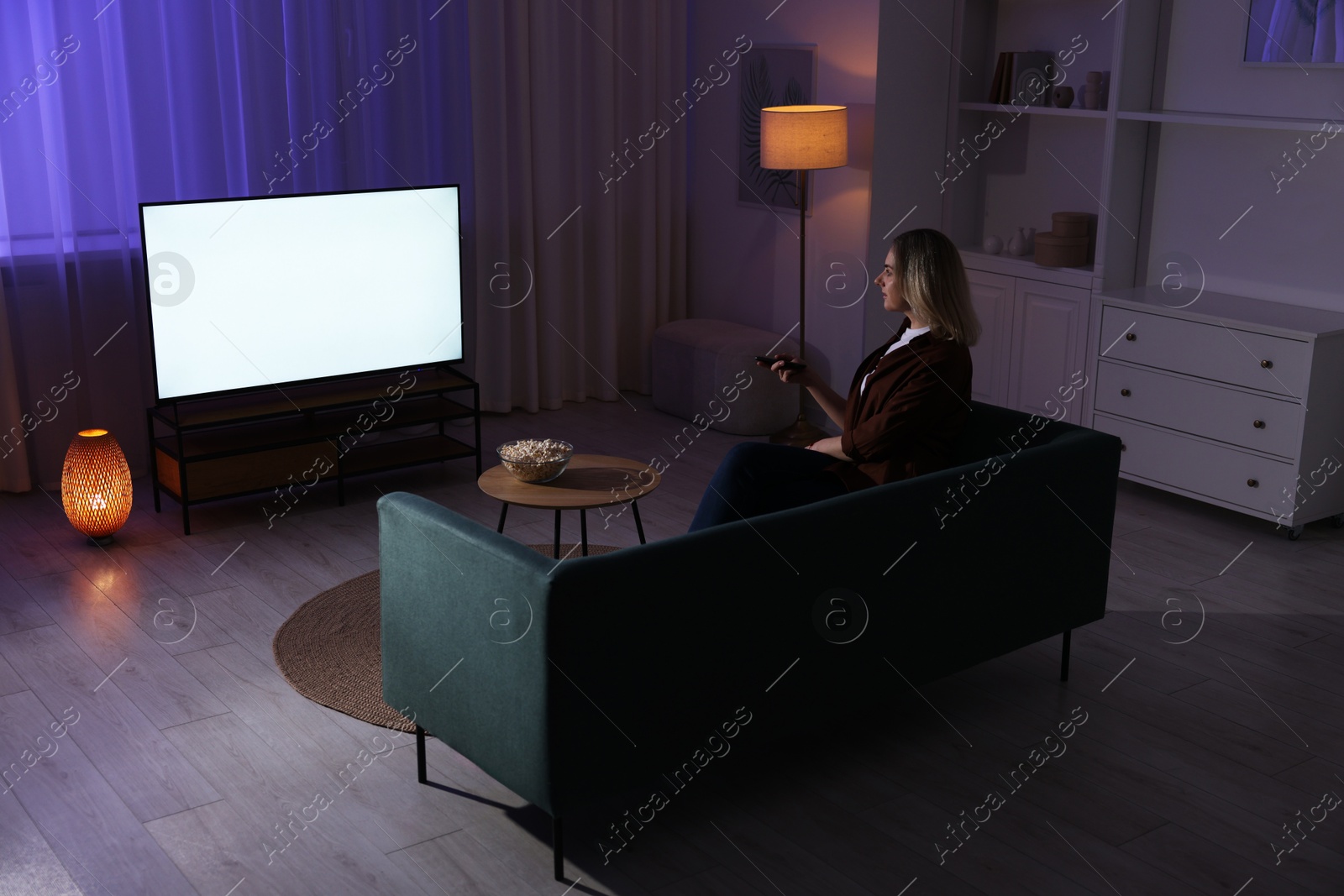 Photo of Woman watching tv at home in evening