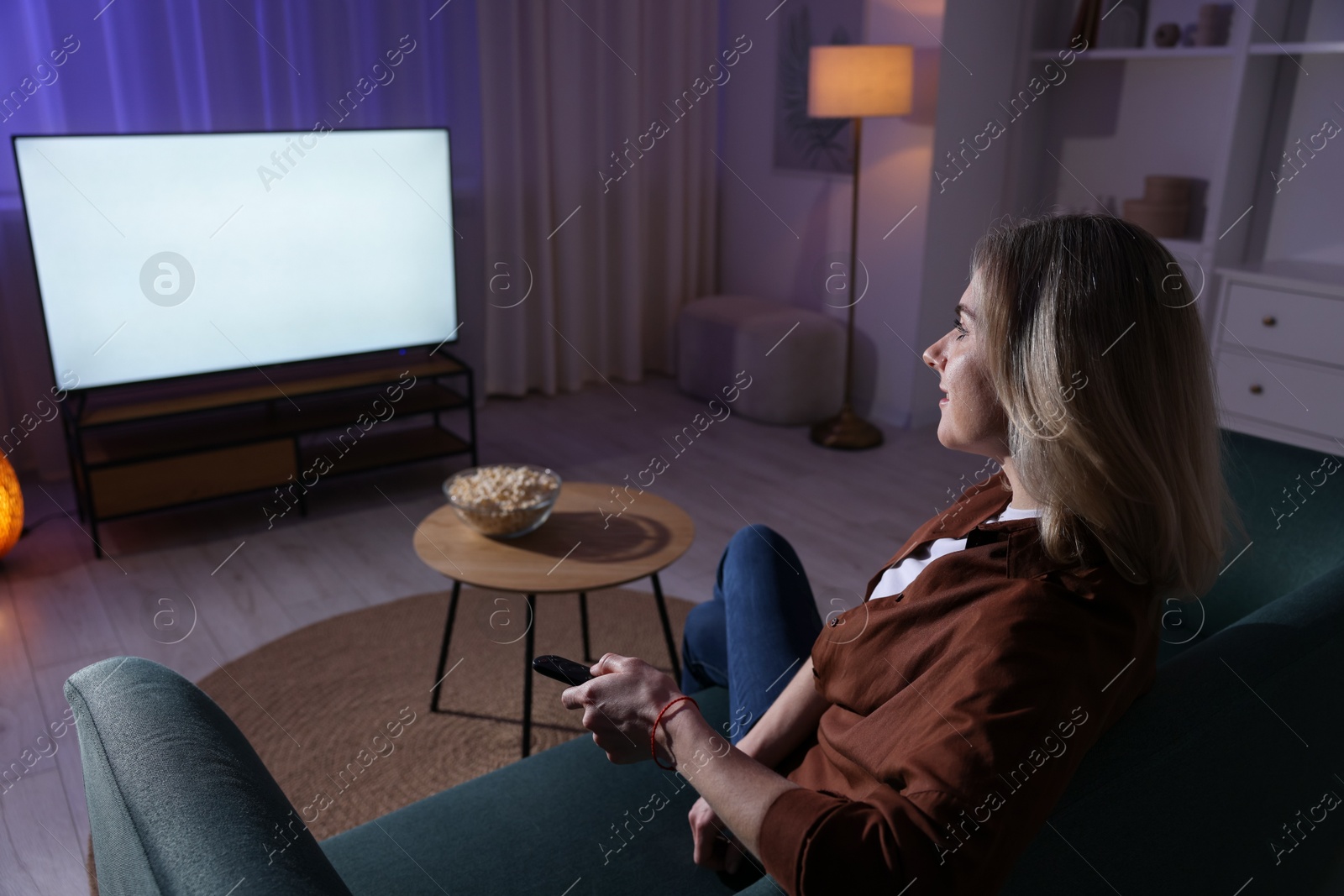 Photo of Woman watching tv at home in evening