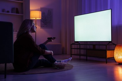 Woman with popcorn watching tv at home in evening