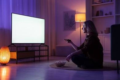 Woman with popcorn watching tv at home in evening