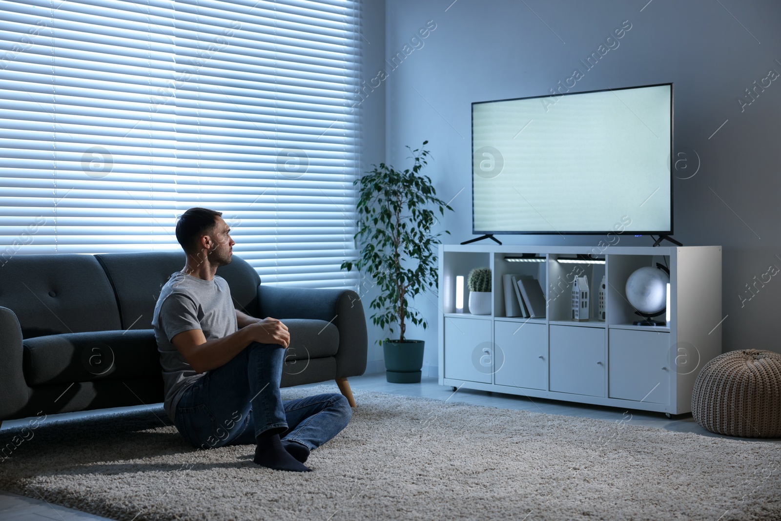 Photo of Man watching tv on floor at home